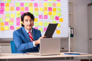 Young handsome employee with many conflicting priorities 