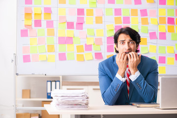 Young handsome employee with many conflicting priorities 