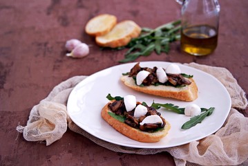 Light snack, crispy bruschetta with champignons, arugula and mozzarella. Italian Cuisine.
