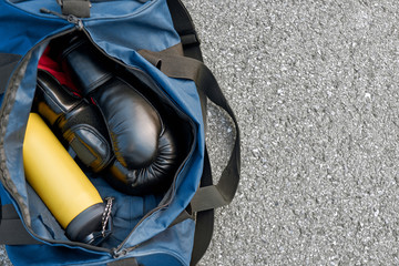 Sports bag and boxing gloves with water at the asphalt background