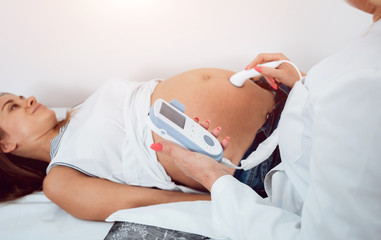 A gynecologist examines a pregnant woman. Fetal doppler heart auscultation. Patient at doctor...