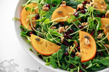 Tasty Persimmon and pea shoot salad with walnuts, pomegranate and pumpkin seed.