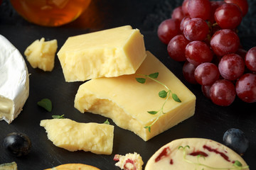 Cheese platter served with grapes, ale chutney, honey, crackers on stone board. Brie, cheddar, red leicester, wensleydale cranberries, blue stilton.