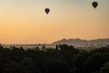 Hot air balloons float above mist as sunrise highlights the temples of Bagan, Myanmar