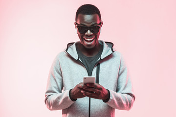 Young excited african american man looking at his phone with surprise expression and mouth wide...