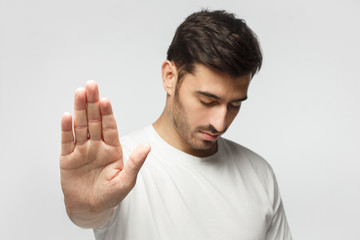 Photo of young man pushing hand forward as if refusing something, wanting to stop, isolated on...