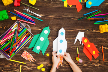 preschool Child in creativity in the home. Happy kid makes rockets from paper. Children's...