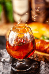 Concept of Georgian restaurant. A girl pours Georgian brandy from a bottle into a glass. On a wooden table is hachipuri