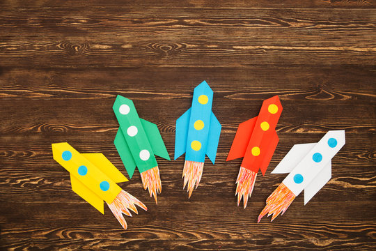top view of flying multi-colored rockets from paper on a wooden background