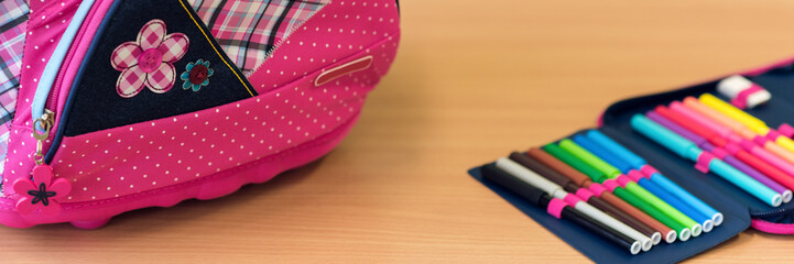 Pink girly school bag and pencil case on a desk against greenboard. First day of school concept.