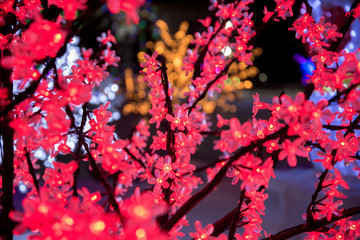 Beautiful glow flower with neon lamp light decorate on tree beside road