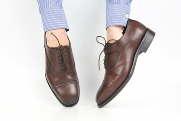 Classic brown shoes worn on the hands on a white background