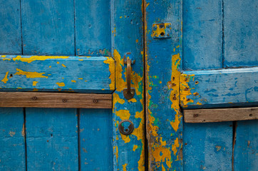 Close up of old wooden door painted in blue with pealing mark and rusty metal handle