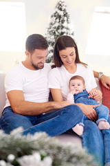 Fototapeta premium Lovely family with their baby girls relaxing on sofa at home