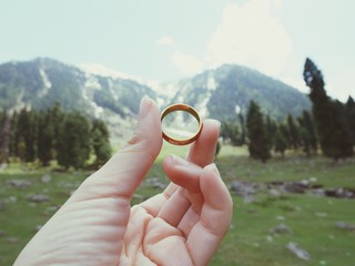 Holding wedding rings in mountain park