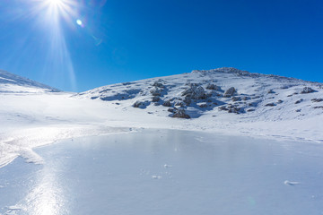 Winter landscape with a frozen lake on a sunny day near mountain Velouchi in Evritania, Greece 