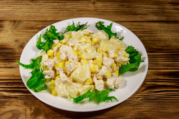 Festive salad with chicken breast, sweet corn, canned pineapple and mayonnaise on wooden table