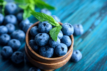 Bowl of fresh blueberries on blue rustic wooden table closeup. - Powered by Adobe