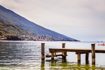 View with wooden dock pier extending over blue lake water and mountains