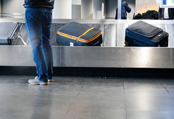 Rear view of a man preparing to take luggage from the conveyor belt in modern Airport