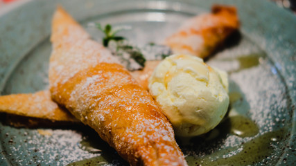 Strudel and ice cream decorated with mint leaf, topping and sugar powder.