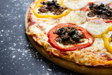 hot tasty delicious rustic homemade american pizza with tomato with thick crust on black table