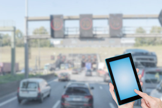 Traffic jam infographic concept. Finger touching tablet blank screen ready for your text. Intentionally blurred image of starting traffic jam in the background. All potential trademarks are removed