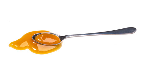 Orange sweet and sour sauce in small metal spoon isolated on white background.