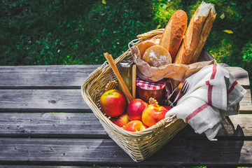 Picnic basket filled with fruit , bread and jar with apricot jam