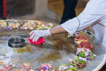 Cooking street food on a large firebox. Frying meat and seafood on the brazier in the street.