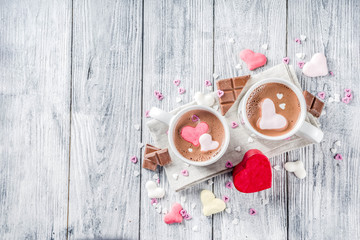 Girl hands hold hot chocolate with marshmallow hearts, red pink white color with chocolate pieces, sugar sprinkles, old wooden background copy space top view, hands in pictute flatlay
