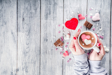 Girl hands hold little heart shaped gift box, old wooden table with hot chocolate with marshmallow...
