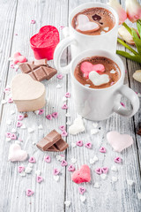Obraz na płótnie Canvas Valentines day treat ideas, two cups hot chocolate drink with marshmallow hearts red pink white color with chocolate pieces, sugar sprinkles, old wooden background copy space top view
