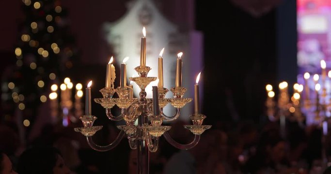 Festive candles at dinner with candlesticks in large dark banquet hall, holiday background.