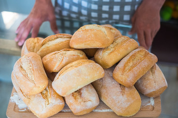 Plate full of fresh ready made bread in bakery or home production - businsss and food store concept with artisan man in background