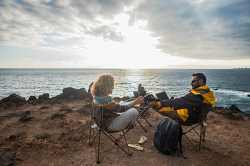 Couple of alternative tourists traveler sit down with the ocean in front and enjoy the rest and the...
