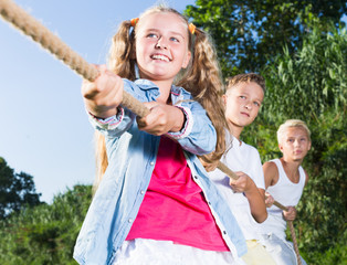 Happy kids tugging war in summer park