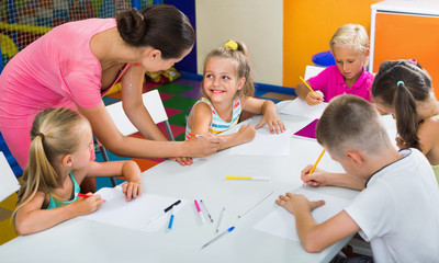 Kids drawing together with tutor at hobby group