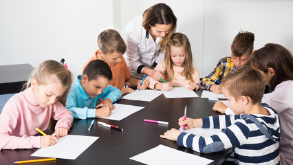 Teacher and elementary age children drawing at classroom
