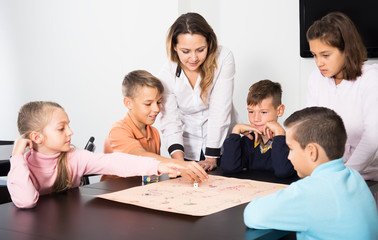 Elementary age happy kids at table with board game and dice