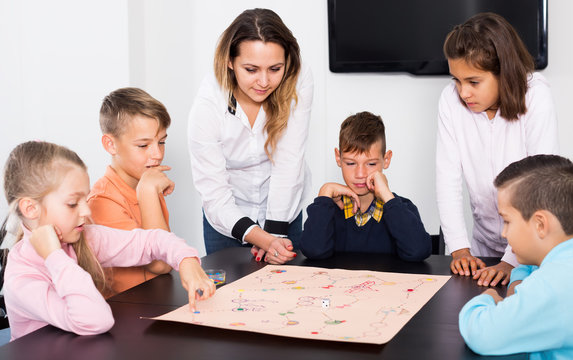 Kids sitting at table with board game in classroom
