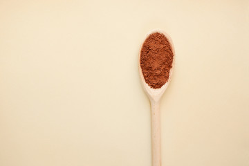 Cocoa powder in a wooden spoon. Top view with copy space