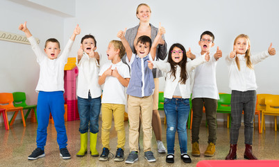 Fototapeta premium Pupils with teacher posing, giving thumbs up