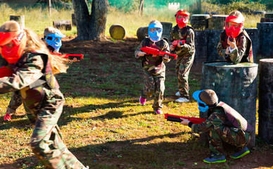 Children paintball players of opposite teams playing in shootout outdoors