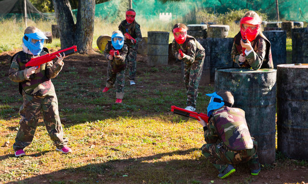 Children paintball players of opposite teams playing in shootout outdoors