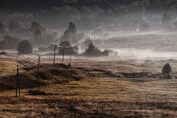 Fog puff over the rural landscape, the power line goes into the distance, the autumn landscape from the height