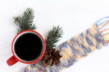Obraz na płótnie Canvas red mug with coffee, a scarf and fir branches with a cone . Warming cosmic drink