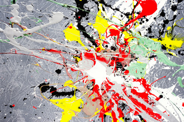a spot of white and black and yellow and green and red spilled paint on a concrete textured surface