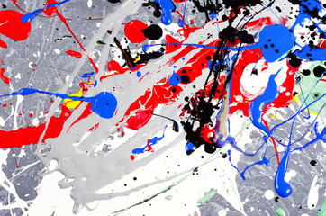 a spot of white and black and yellow and green and red and blue spilled paint on a concrete textured surface