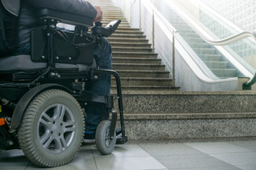 Disabled person on a wheelchair in front of stairs. Accessibility concept